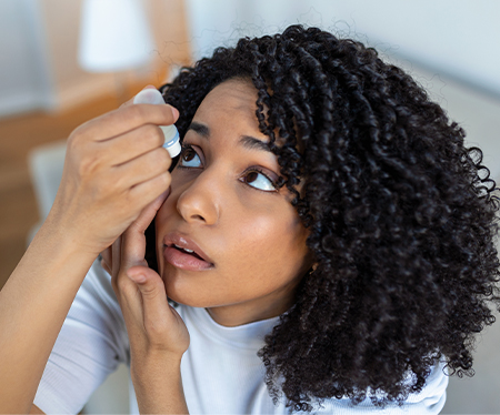 a woman using eye drops to treat dry eye