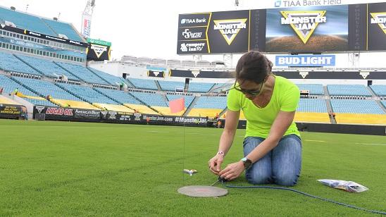 Dr. Bridge kneels while working on some wires on the Monster Jam field.