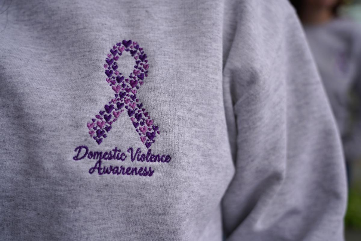 Sweatshirt with embroidered purple ribbon for domestic violence awareness month