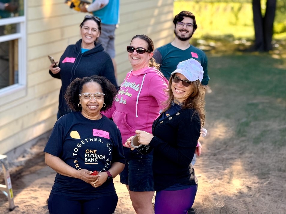 3 women in habitat hard hats engaged in lively conversation