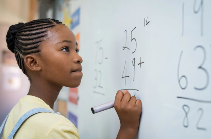 Girl doing math problems at a whiteboard
