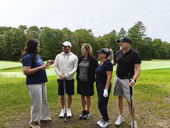 Woman talking with four people on a golf course