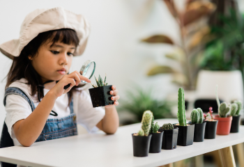 Young girl looking at plants through a magnifying glass