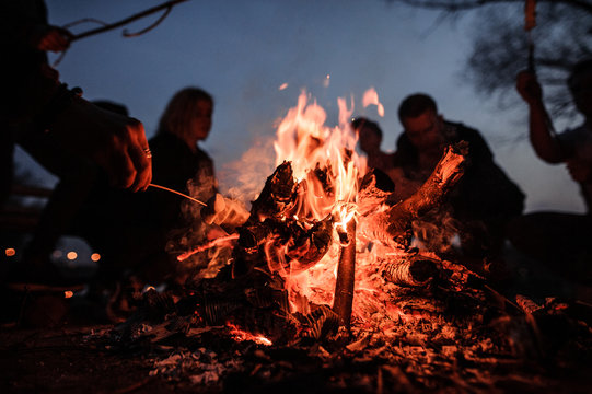 4 adults around a bonfire roasting smores.