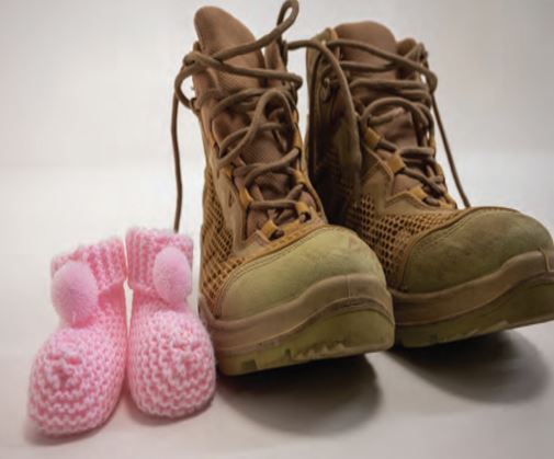 pink baby booties sitting next to combat boots
