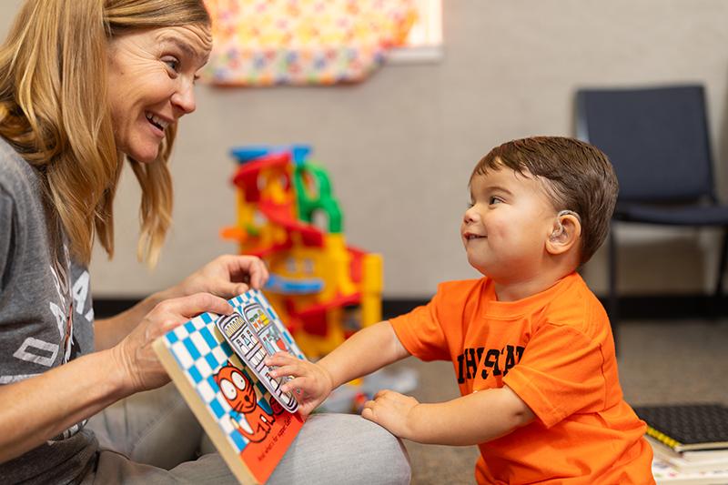Child with cochlear implants reading a book with his mother