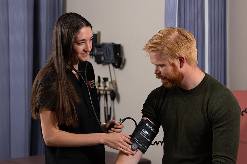 Physician assistant studies students check each other's blood pressure during a course assignment.