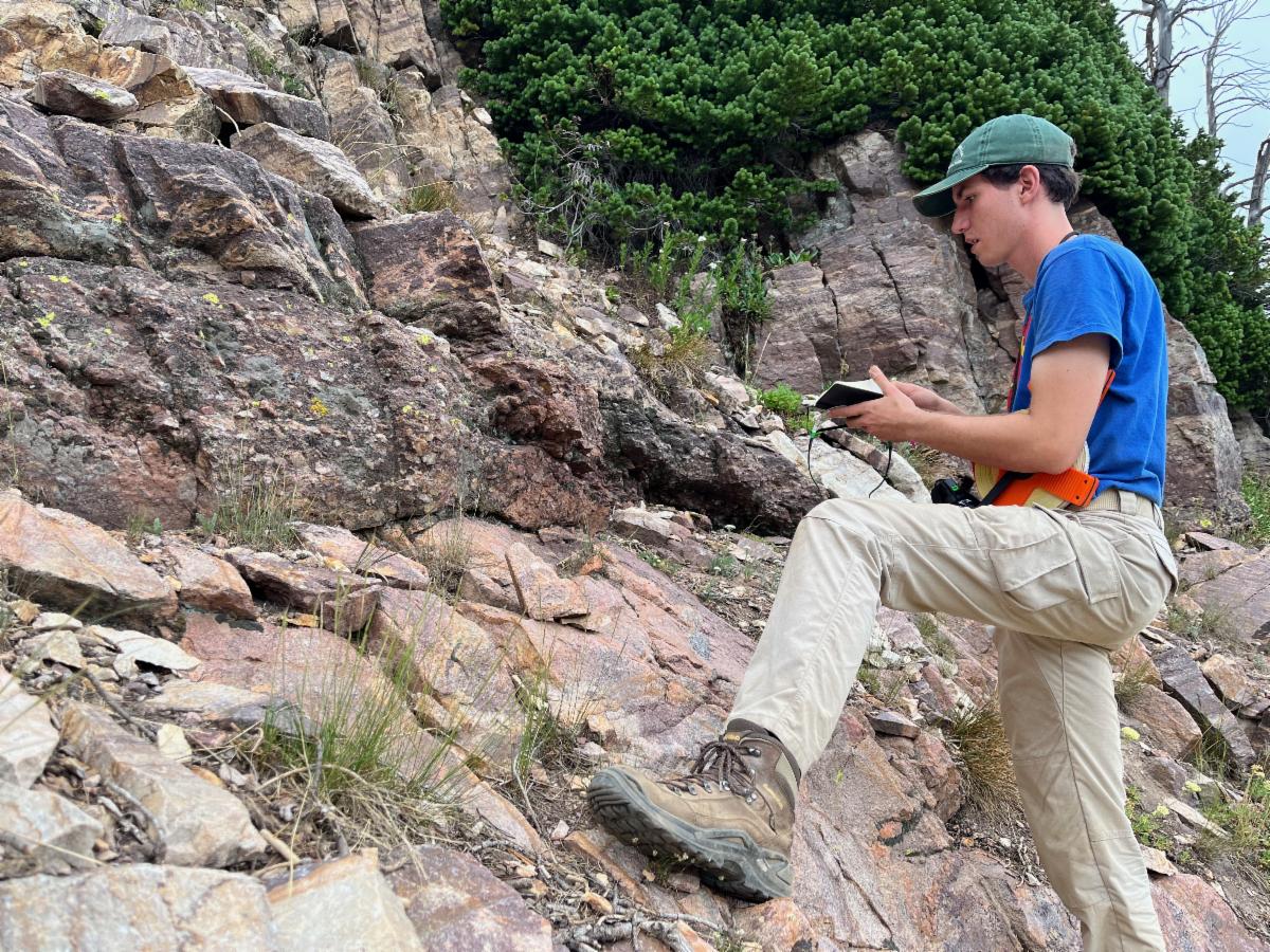 Zachary Ellia graduate student at Idaho State University examines an exposure of the Great Unconformity in the Teton Range