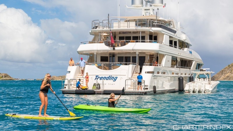 Motor yacht TRENDING with passengers lounging and on paddleboards off bow