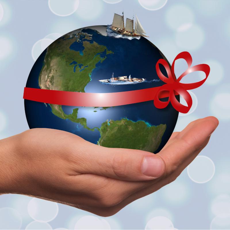 Globe with a ribbon and boats offered by a hand
