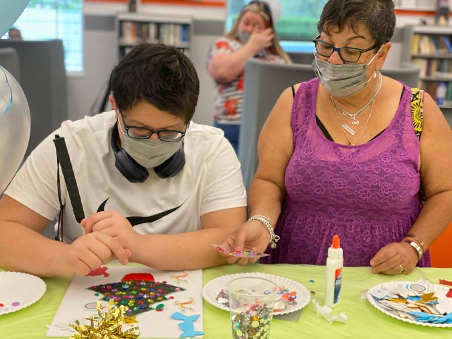 Blind young man making a craft with the help of mom