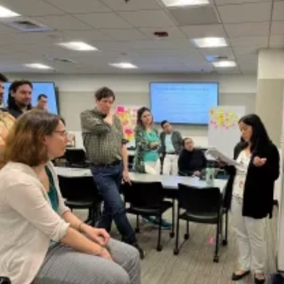 Nine participants meet in May 2023 to discuss potential program elements at the first CONVEI workshop. Around the room are large pieces of white paper filled with colored sticky notes and brainstorming ideas.