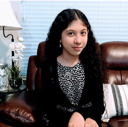 A young woman sitting on a couch in a black blazer