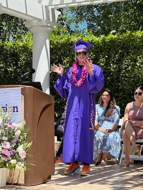 Otto is pictured here dressed in a purple graduation gown giving a high school graduation speech.