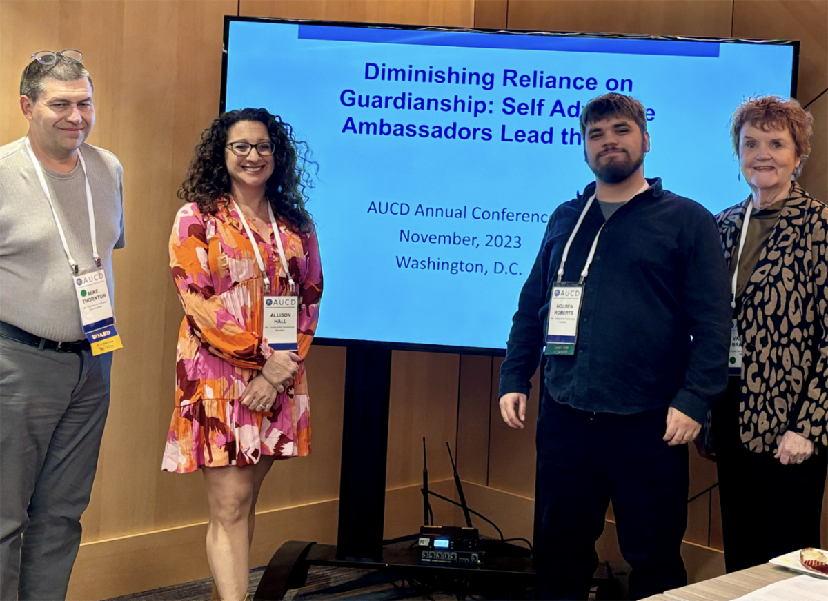 Four people stand in front of a screen