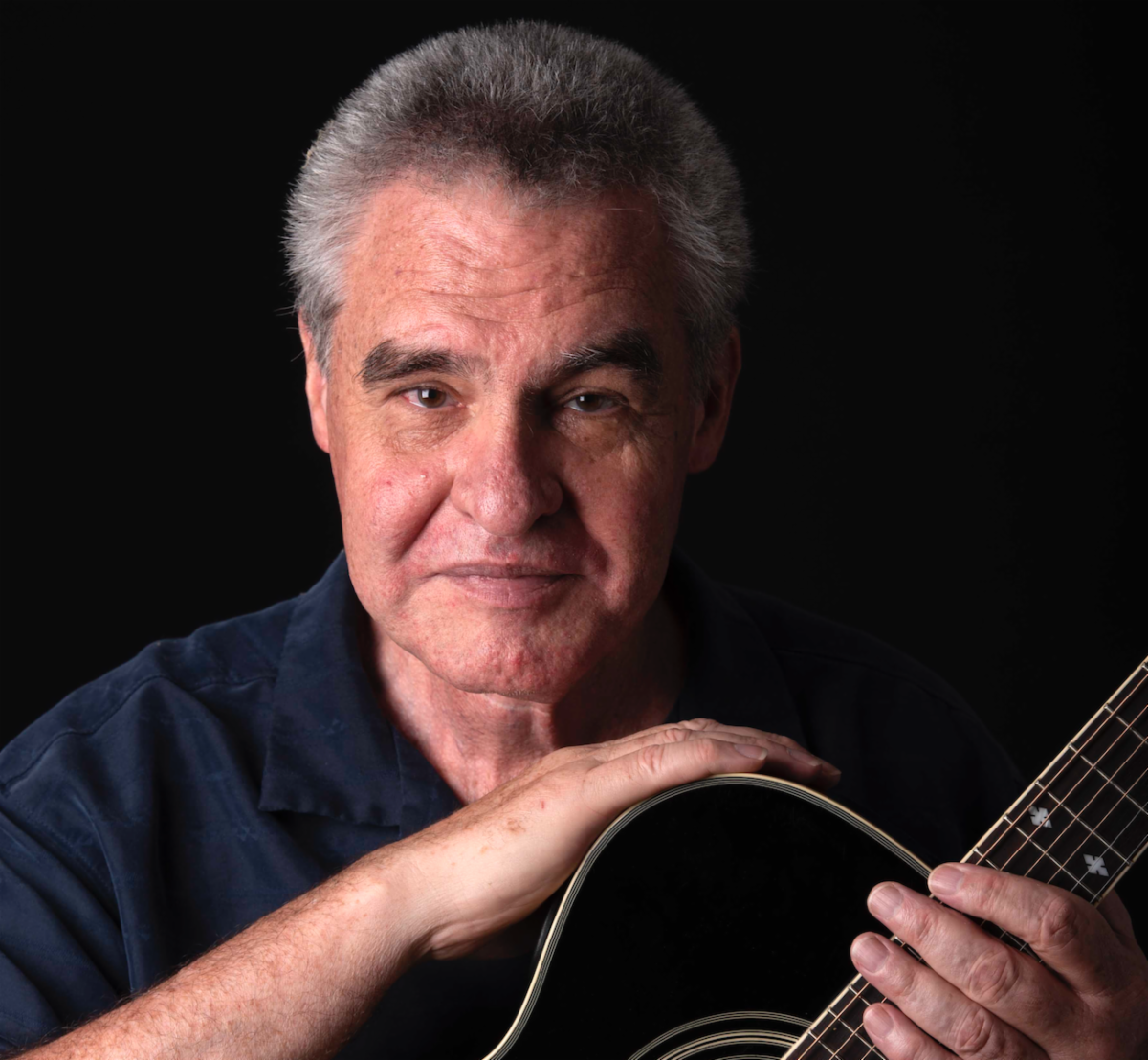 Portrait photo of Dillion with guitar on black background