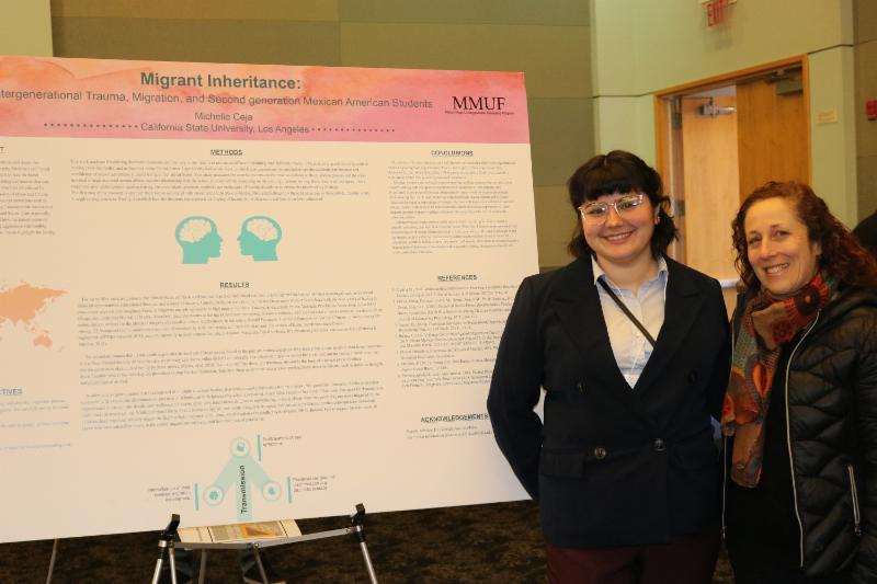 Student and professor posing in front of presentatio poster in hall. 