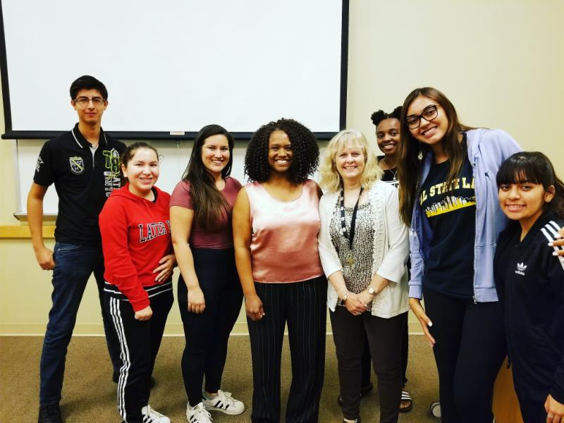 Six students from the pre-med club posing with Dr. McQueen and a female guest speaker