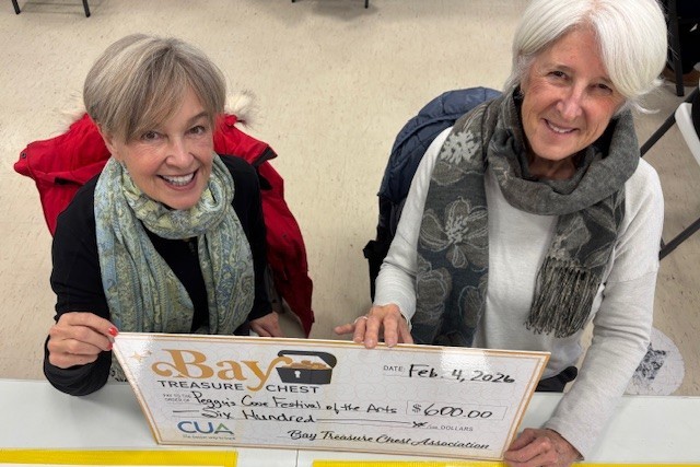 women wearing a scarf with another woman in a white top holding an oversized honorarium cheque