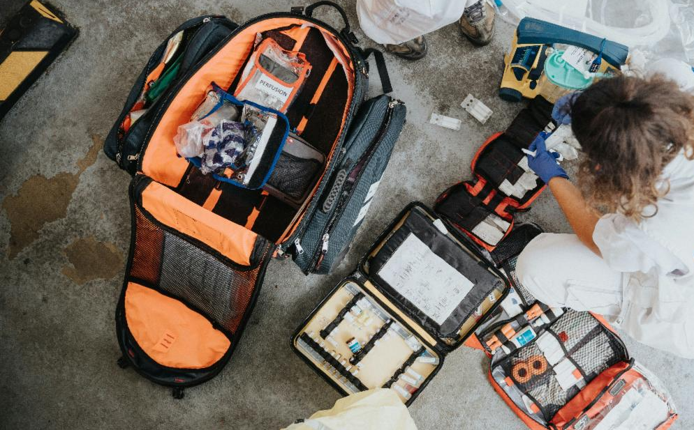 birds-eye photo of a person crouching next to a pile of medical humanitarian aid supplies