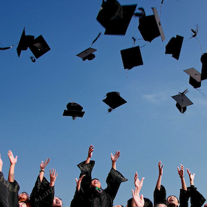 Stock photo of graduates throwing their caps in the air