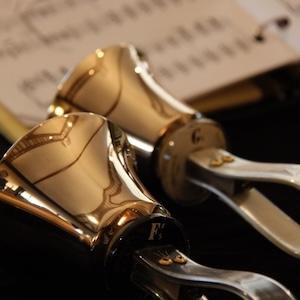 Photo of two gold hand bells resting on sheet music