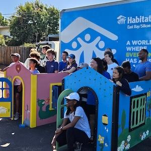 Photo of volunteers standing inside the playhouses they built