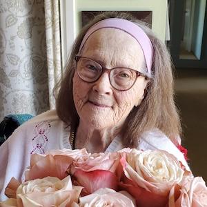 Smiling headshot of Maggie Burklund with pink roses