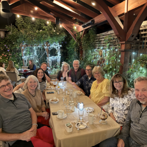Photo of ten adults around a long table at a backyard dinner party