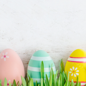 Photo of 3 painted wooden Easter eggs in grass