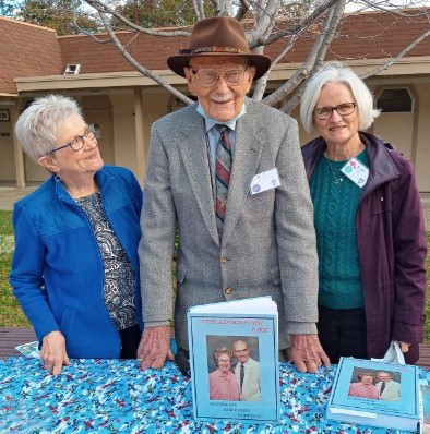 Judi and Ralph and Mary smiling behind the book table in Trinity Court