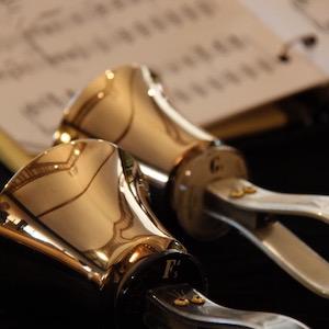 Close-up of handbells resting on a table with sheet music