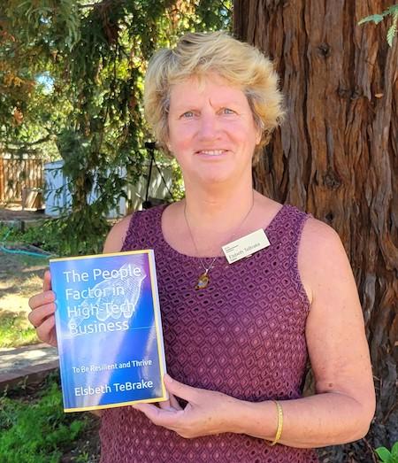 Elsbeth TeBrake holding her book and standing in front of a tree 