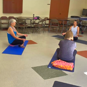 Photo of three adults on yoga mats