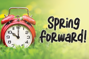 an old-fashioned alarm clock in green grass with the words SPRING FORWARD in a playful font