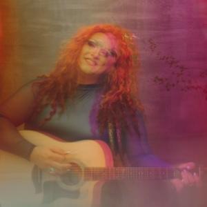 rainbow filter on an artistically blurry photo of Flamy Grant playing a guitar