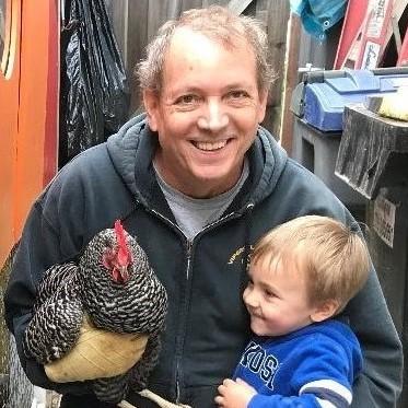 Richard Collins holding his grandson and a chicken