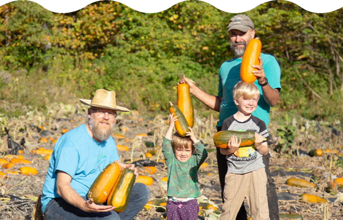 Two adults and two children in a squash patch.