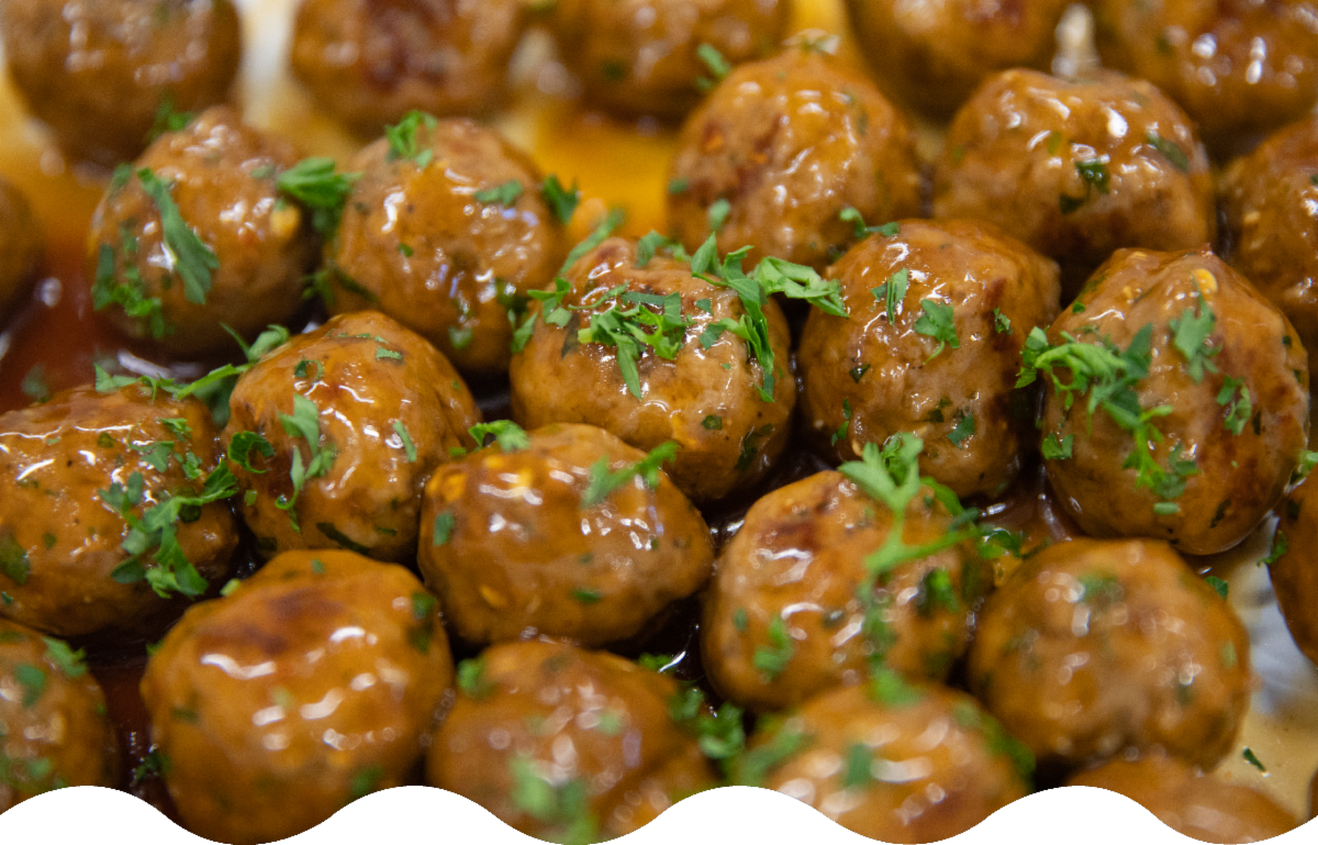 Close-up of glazed meatballs garnished with chopped parsley.