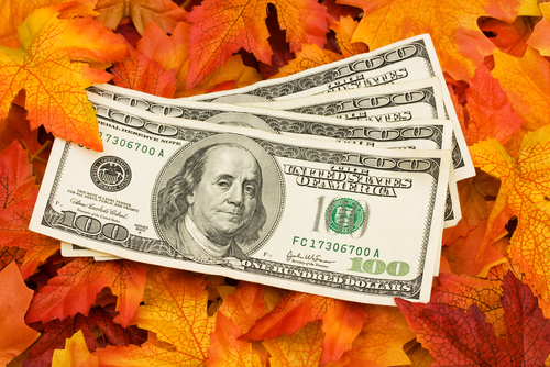 Four one hundred dollar bills sitting on a fall leaf background_ money