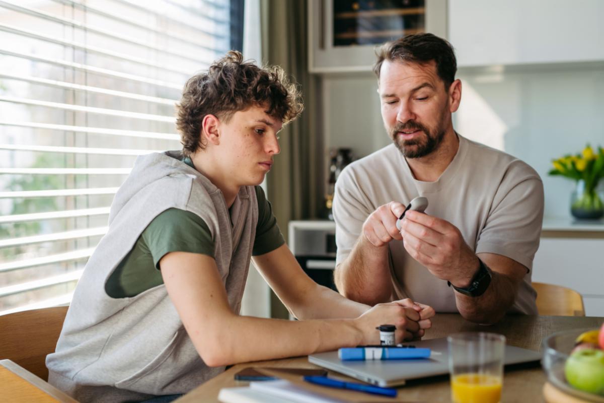 Older man showing a young adult how to use an insulin pen