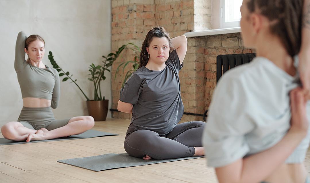 young adult woman with Down syndrome practicing yoga with others in a studio