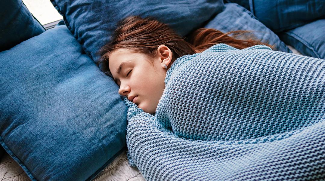 teen girl sleeping in a warm blue blanket