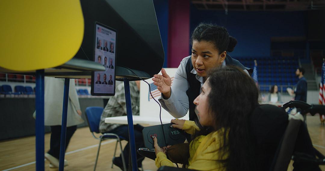 Polling officer consults woman with physical disability at a voting machine