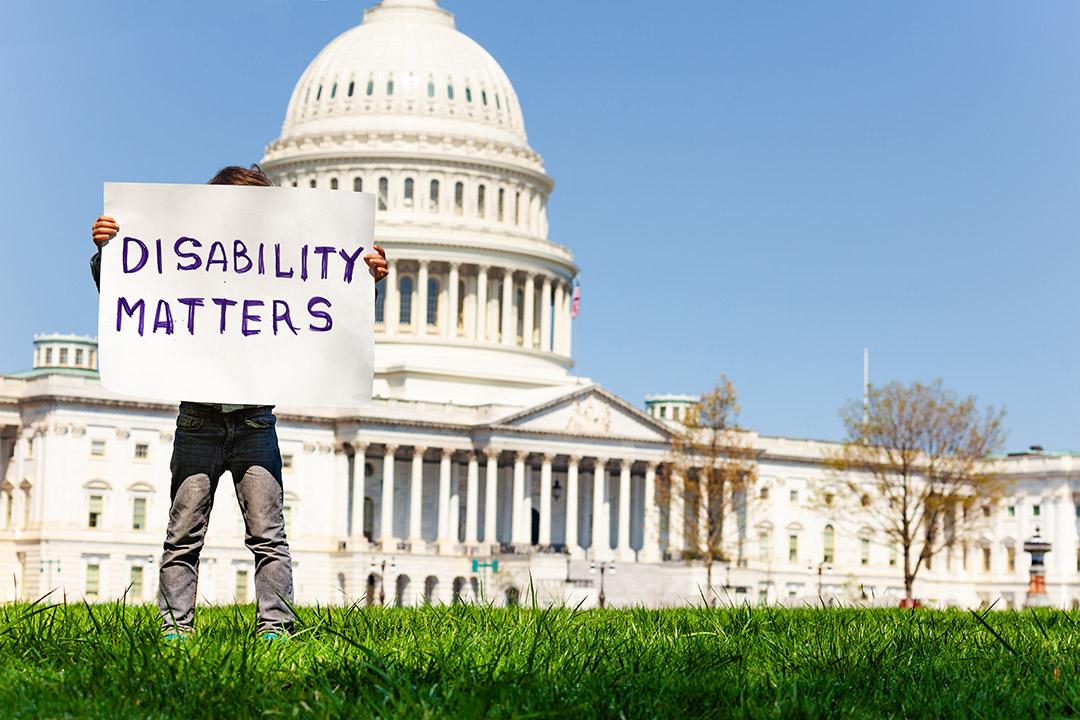 Boy with sign saying "Disability Matters" standiong in front of the US capitol Building