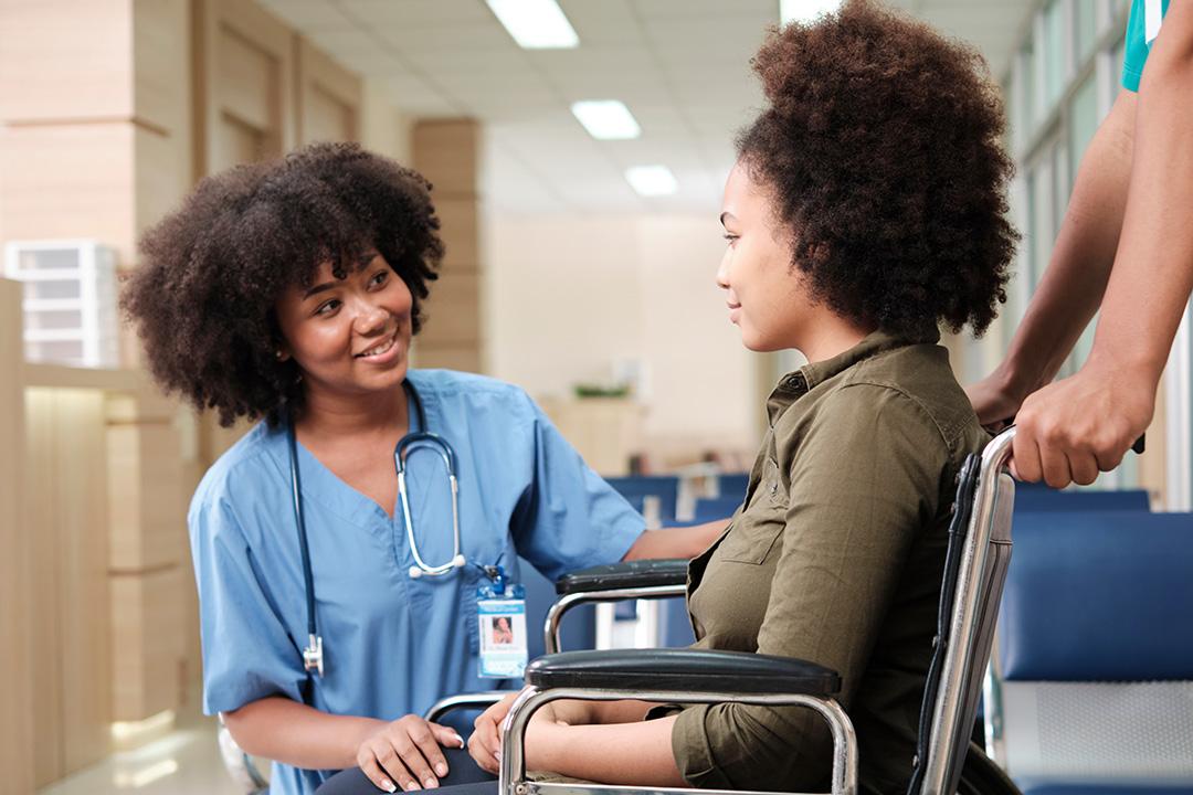 Female teen using a wheelchair and talking with her female medicala doctor