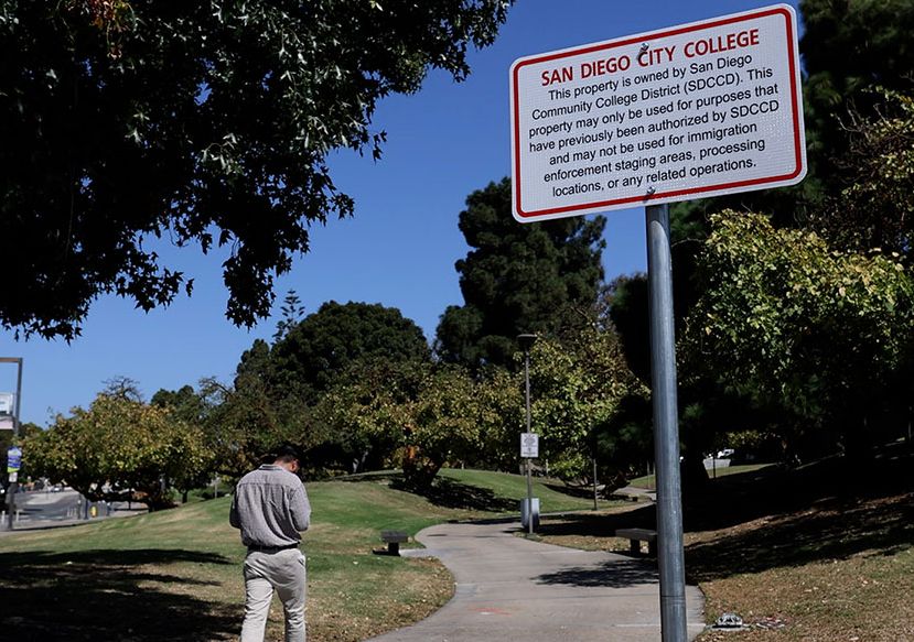 A white and red sign along a pathway at City College