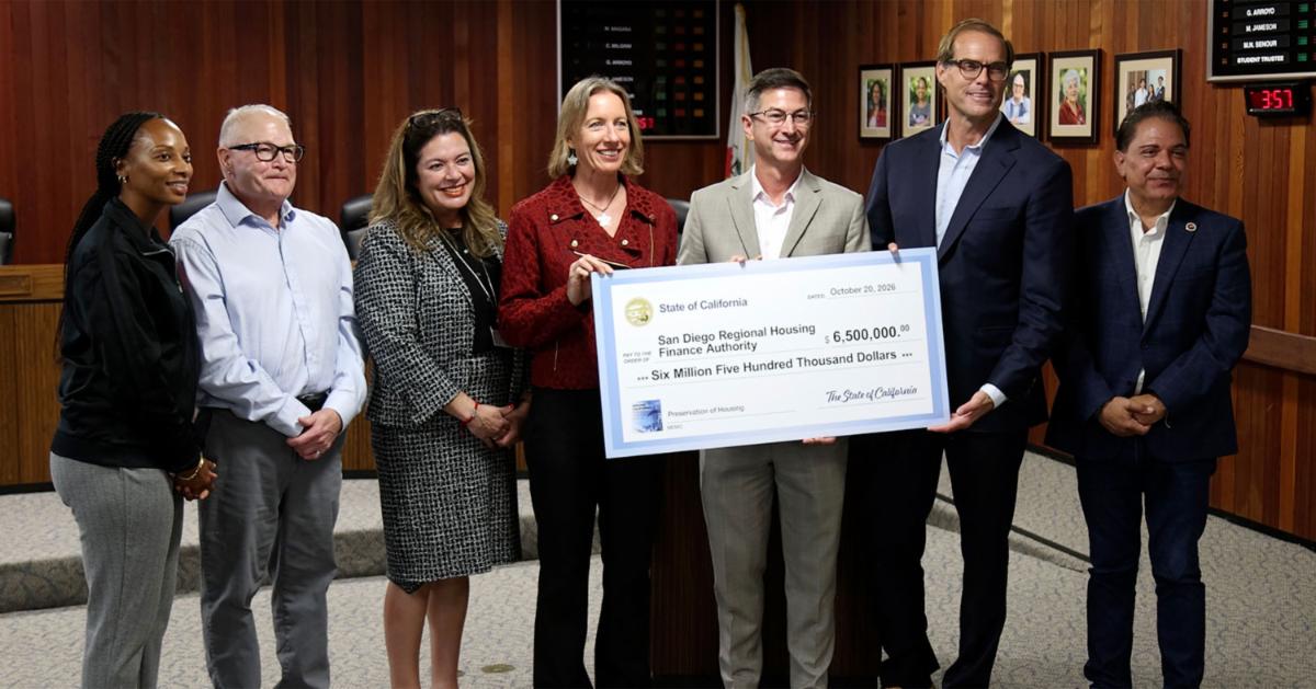 Seven people hold a large check for $6.5 million