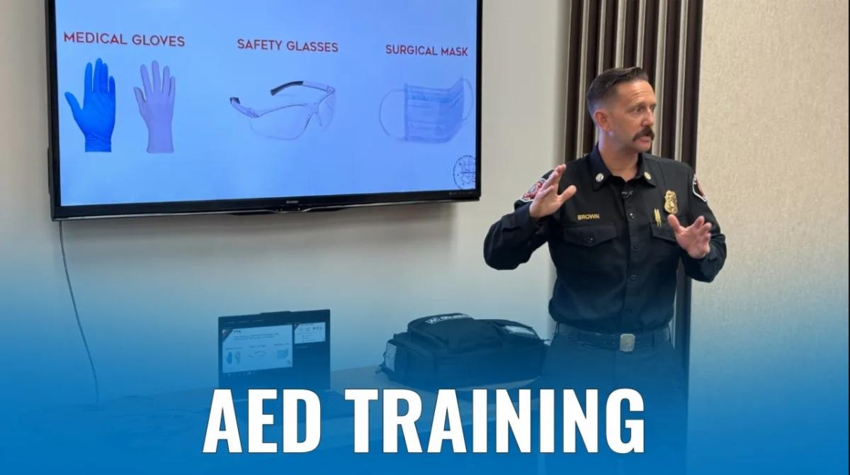 Firefighter giving AED instruction in classroom setting.