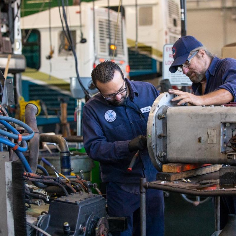 two individuals working on an engine